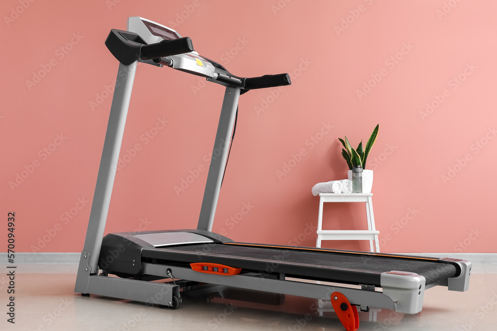 Interior of room with modern treadmill near pink wall