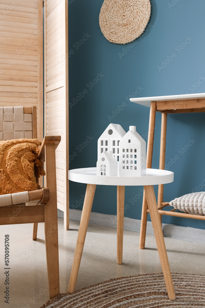 Interior of living room with house candle holders on end table near blue wall