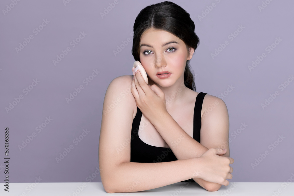 Facial cosmetic makeup concept. Closeup portrait of young charming girl applying dry powder foundati