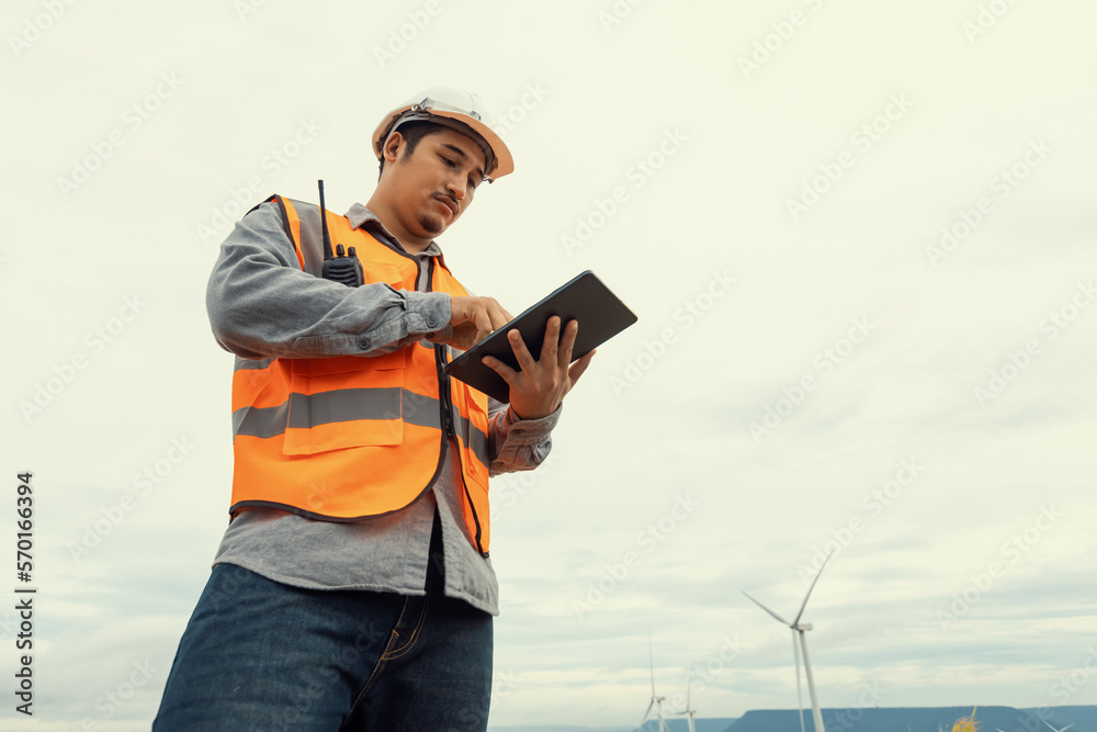 Engineer working on a wind farm atop a hill or mountain in the rural. Progressive ideal for the futu