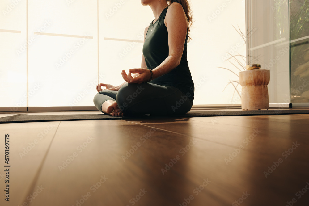 Mature woman practicing sukhasana at home