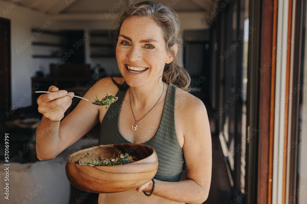 Happy vegan woman eating a vegetable salad from a bowl