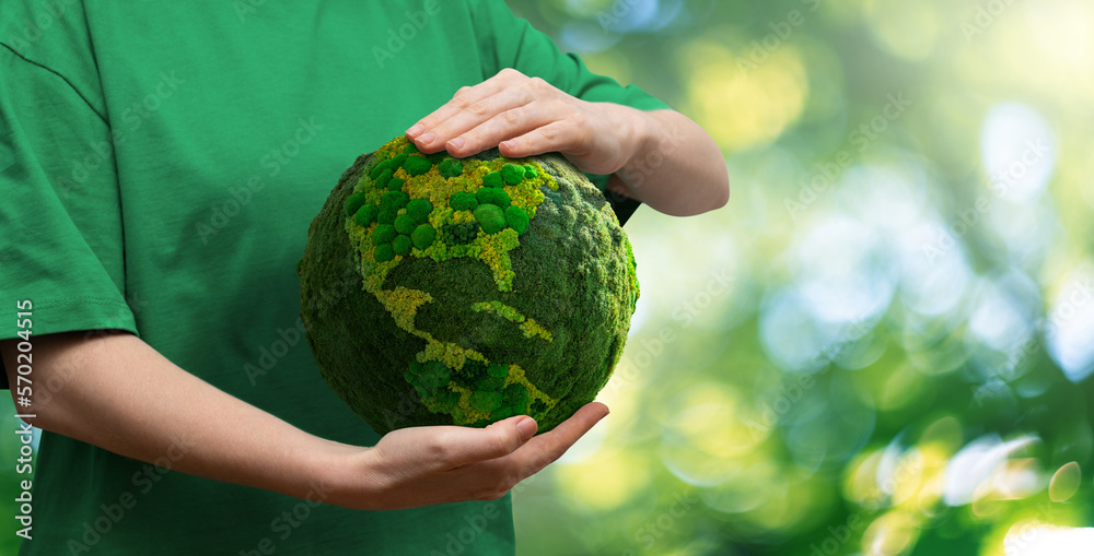 Woman  holds a green planet Earth on a green background. Symbol of sustainable development and renew