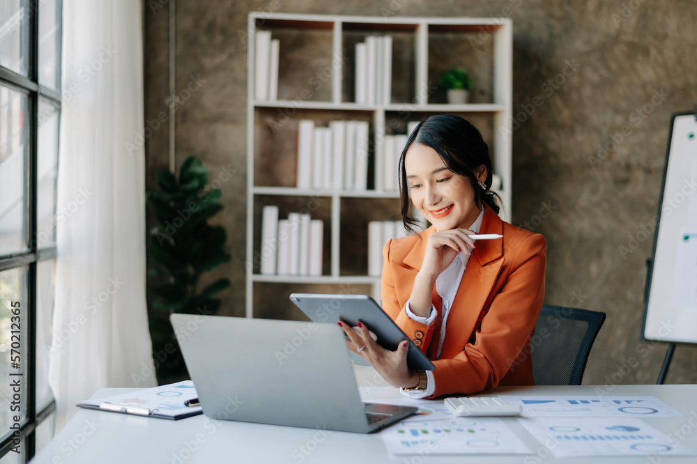 Young beautiful woman using laptop and tablet while sitting at her working place. Concentrated at wo