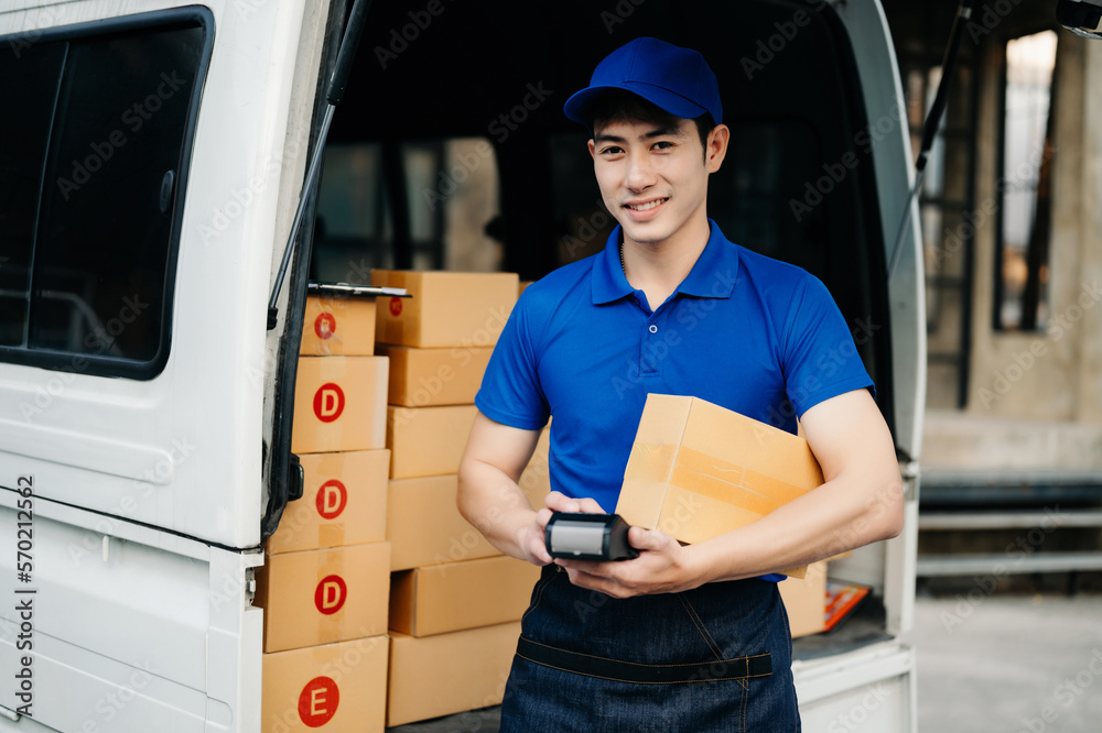 Happy delivery man standing with arms crossed near van outside the warehouse. This is a freight tran