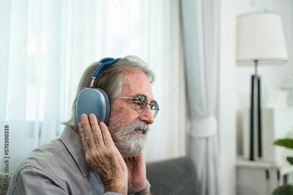 Senior man listening to music with headphones,Relaxed in sofa at his home.