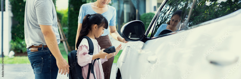 Progressive young happy family with electric vehicle and home backyard charging station. Green and c