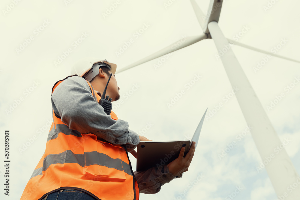 Engineer working on a wind farm atop a hill or mountain in the rural. Progressive ideal for the futu