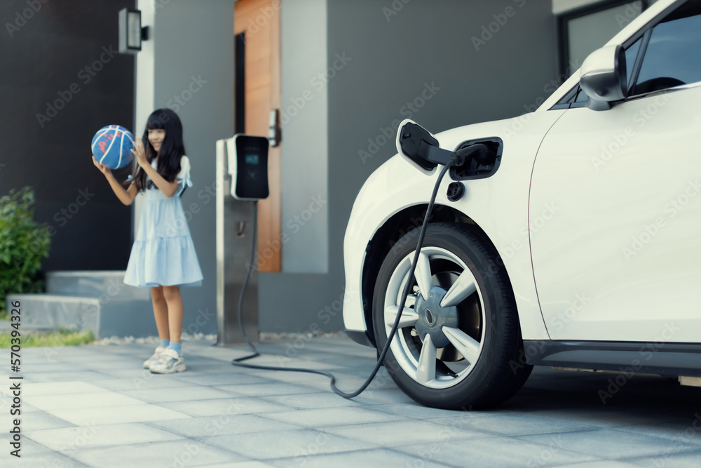 A playful and happy girl playing around at her home charging station providing a sustainable power s