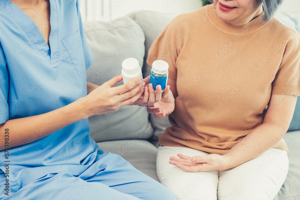 Caregiver advising contented senior woman on medication in the living room. Medication for seniors, 