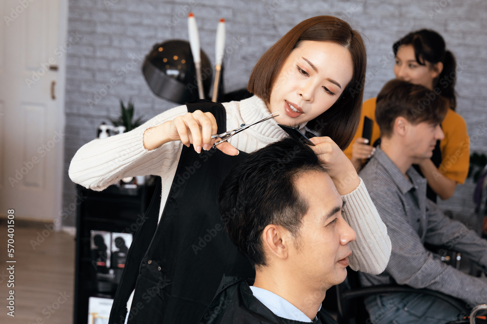 Asian female hairdresser making haircut for two male customer with male hairstyle in qualified barbe