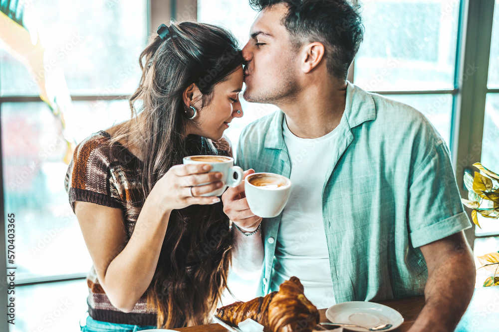 Happy couple enjoying breakfast drinking coffee at bar cafeteria - Life style concept with guy and g