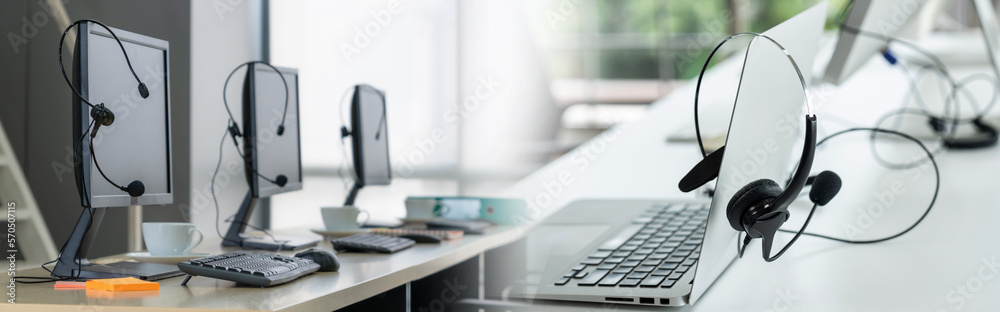 Call center computers and headsets all in office in widen view. Telemarketing, customer support agen