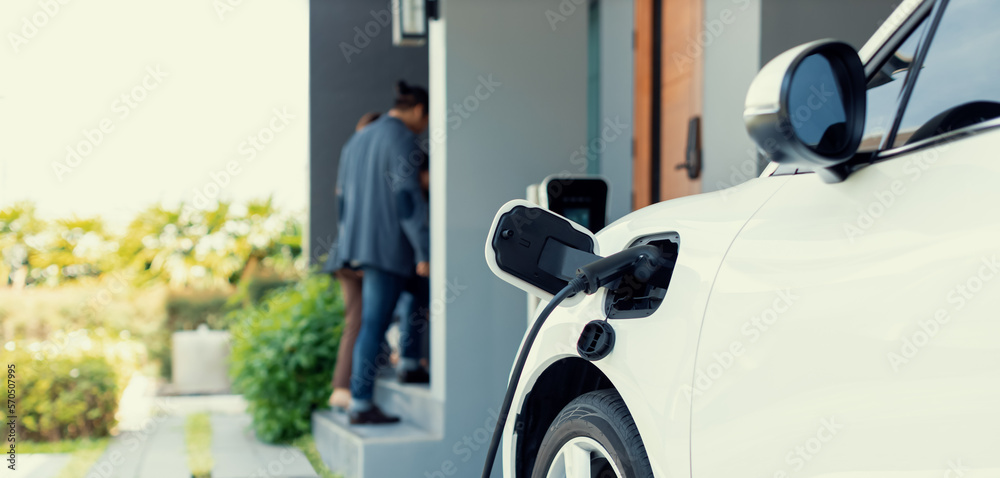 Focus closeup electric vehicle recharging battery from home electric charging station with blurred f