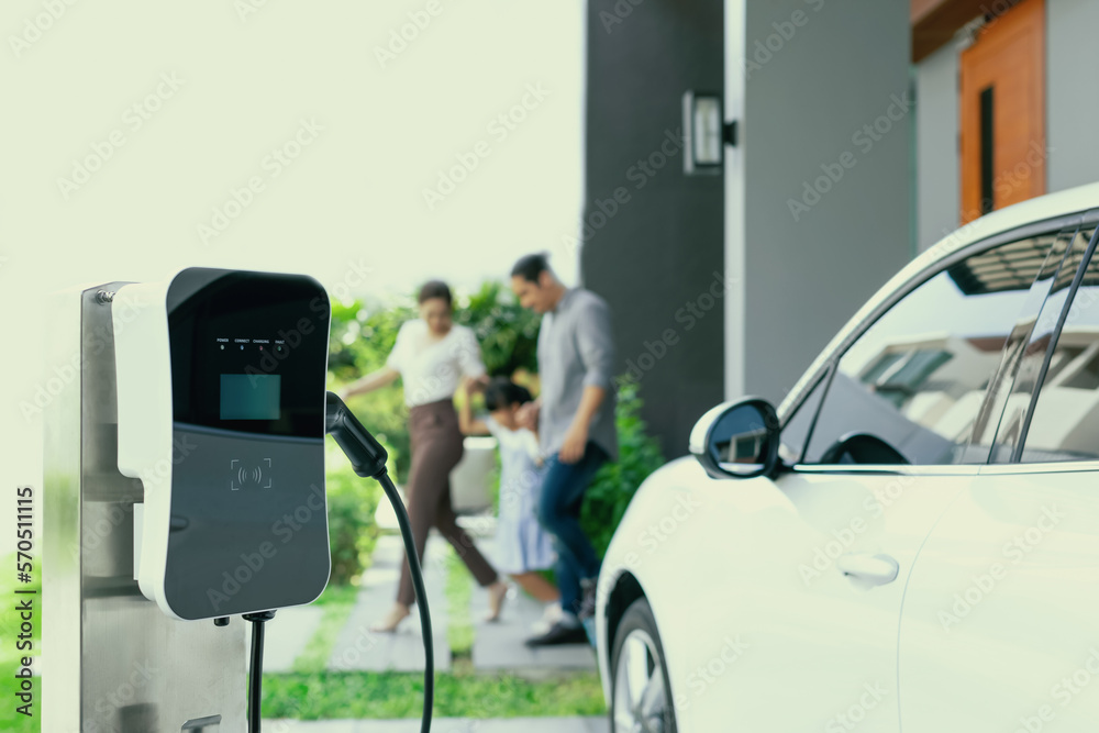 Focus closeup electric vehicle recharging battery from home electric charging station with blurred f