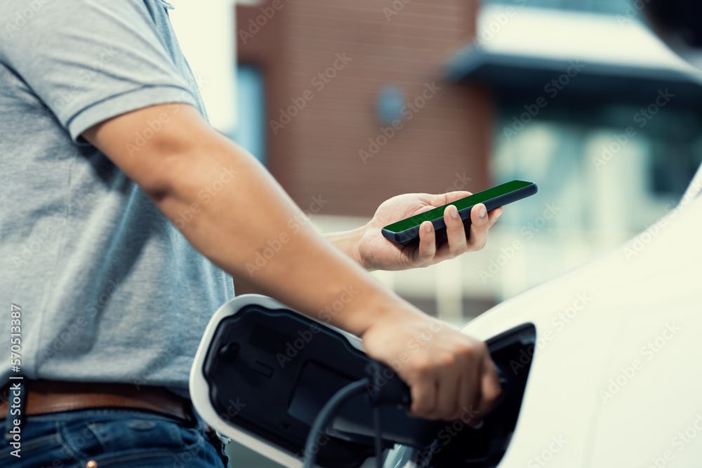 Mockup phone with green screen display energy status of electric vehicle connected to charging stati