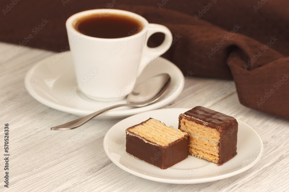 Sweet waffles in chocolate with cup of hot homemade coffee espresso on white wooden table