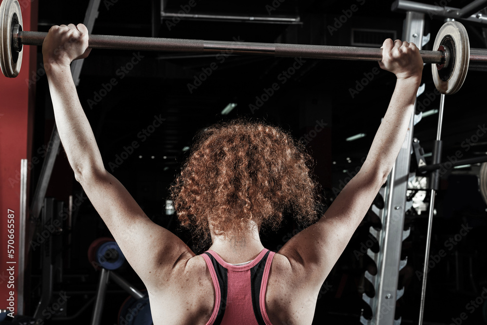 Woman bodybuilder engaged with a barbell in the gym