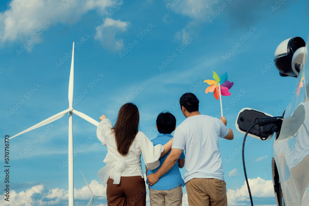 Progressive happy family enjoying their time at wind farm for green energy production concept. Wind 