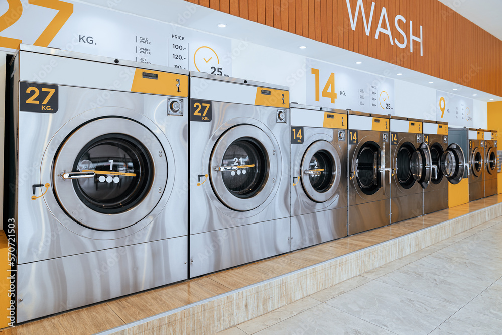 A row of qualified coin-operated washing machines in a public store. Concept of a self service comme