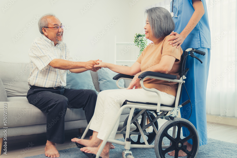 A contented senior couple and their in-home nurse. Elderly female in wheelchair with her young careg