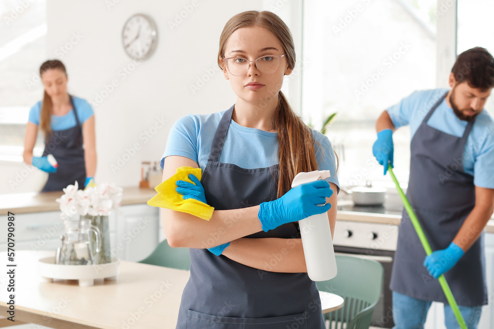 Female janitor with rag and detergent in kitchen