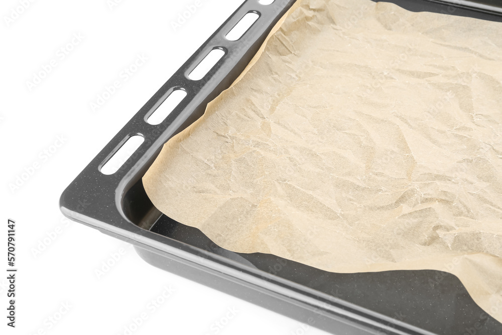 Baking sheet with paper on white background, closeup