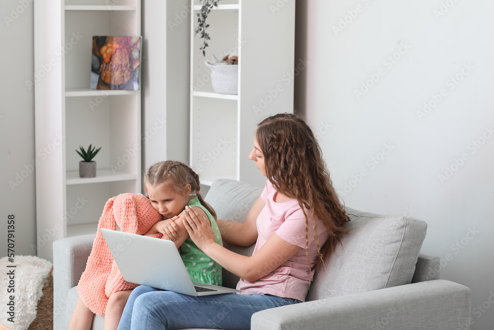 Upset little girl with toy and her mother having online psychologist session at home