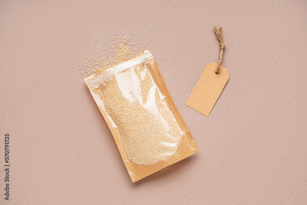 Paper bag with amaranth seeds and tag on color background