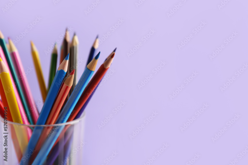 Glass of colorful pencils on lilac background, closeup