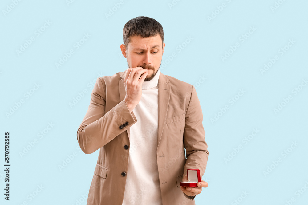 Handsome businessman biting nails on blue background