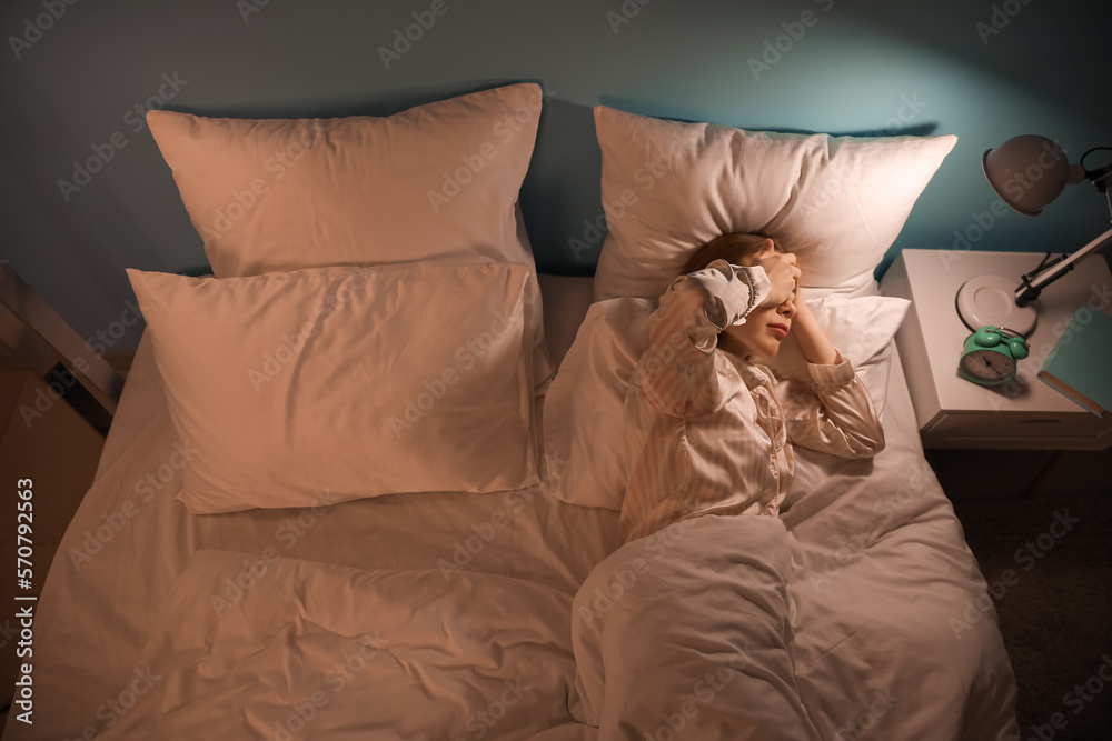 Young woman lying in bed at night