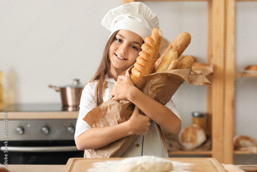 Little baker with tasty baguettes in kitchen