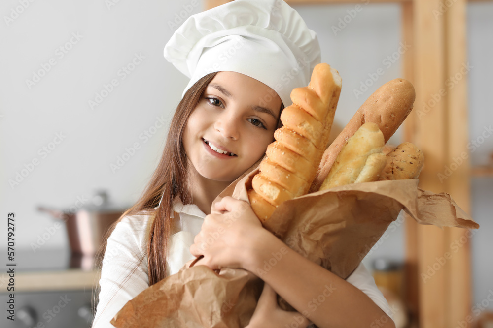 Little baker with tasty baguettes in kitchen, closeup