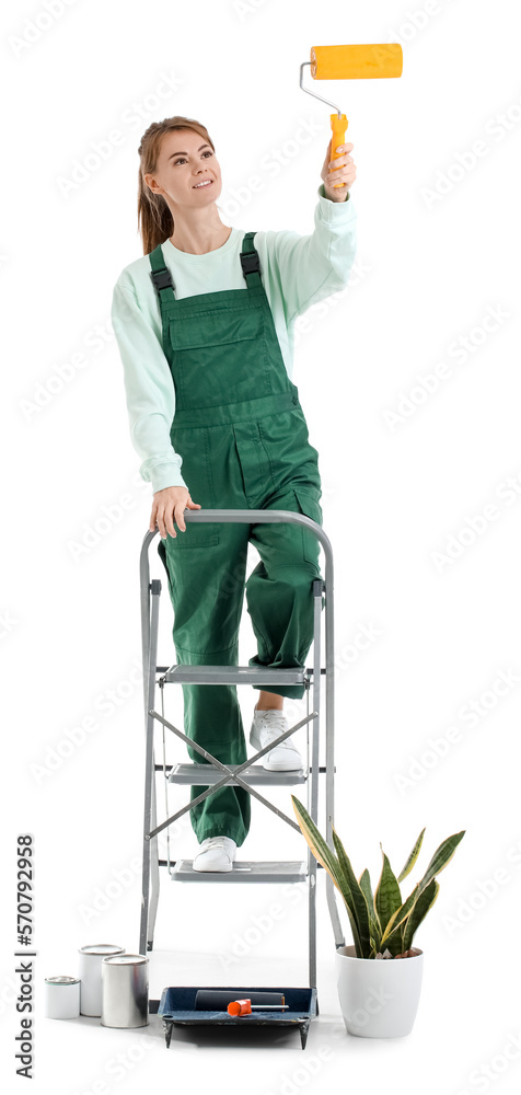 Young woman with roller, ladder, houseplant and paint cans on white background