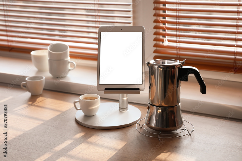 Grid with geyser coffee maker, stand with tablet computer and cup of espresso on kitchen counter