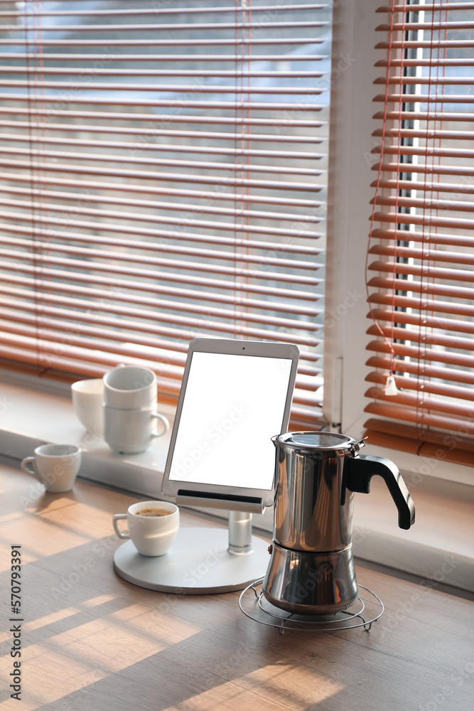 Grid with geyser coffee maker, stand with tablet computer and cup of espresso on kitchen counter