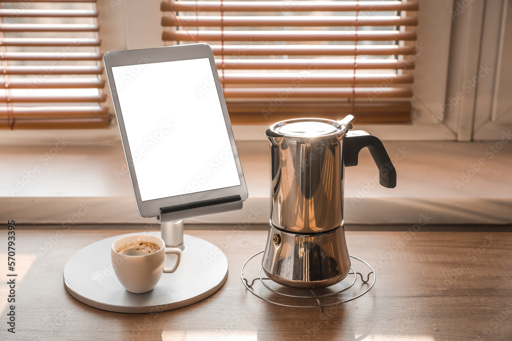 Grid with geyser coffee maker, stand with tablet computer and cup of espresso on kitchen counter