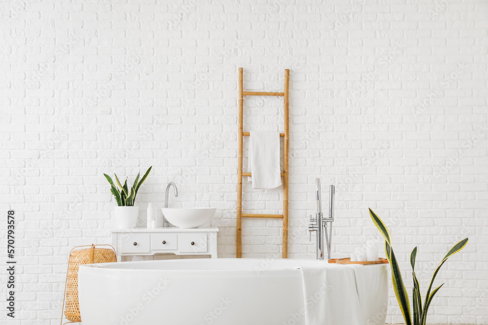 Interior of light bathroom with bathtub, sink and ladder