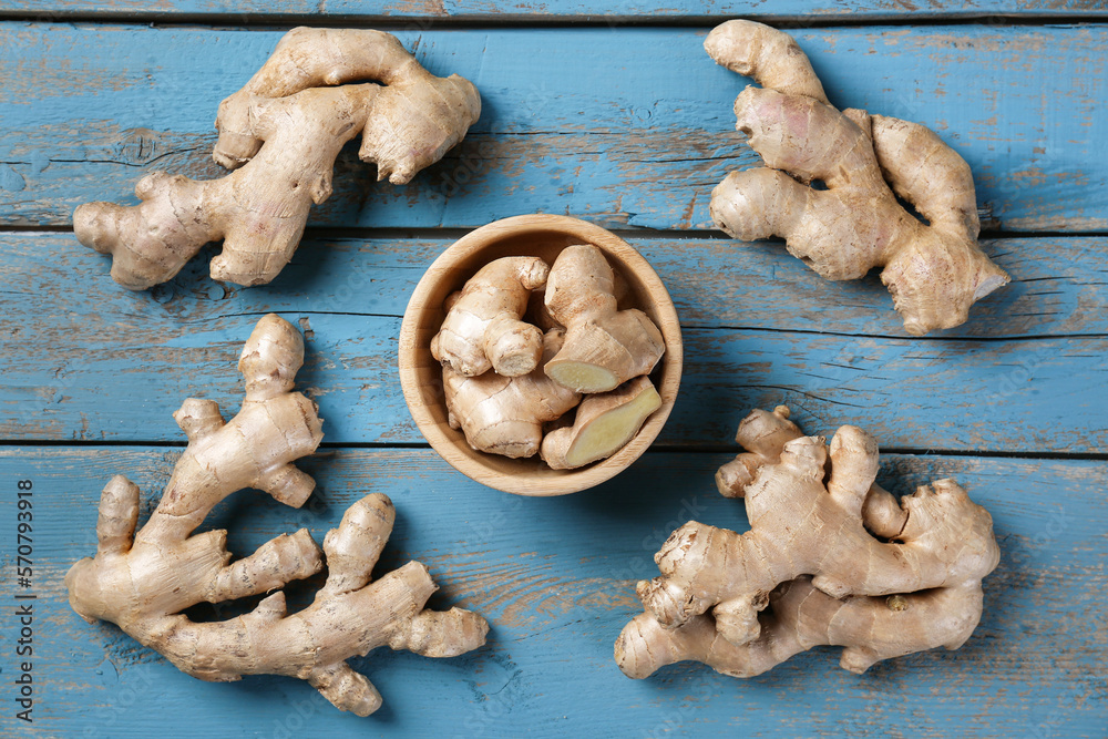 Bowl with ginger roots on blue wooden background