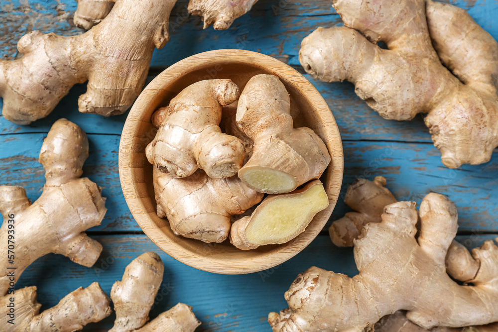 Bowl with ginger roots on wooden table, closeup