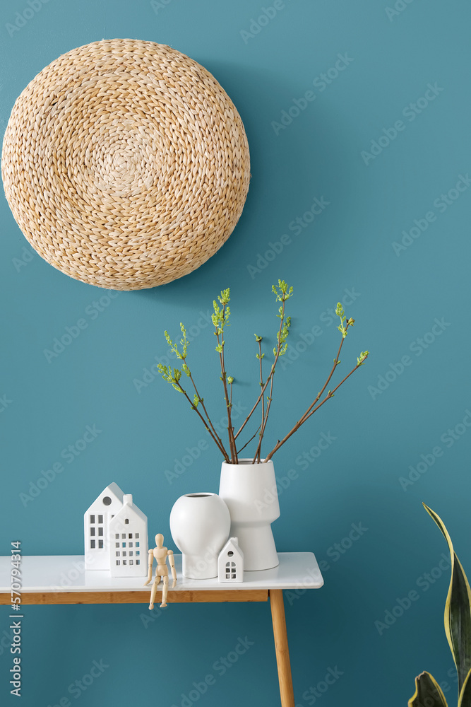 House candle holders, wooden mannequin and houseplant on table near blue wall