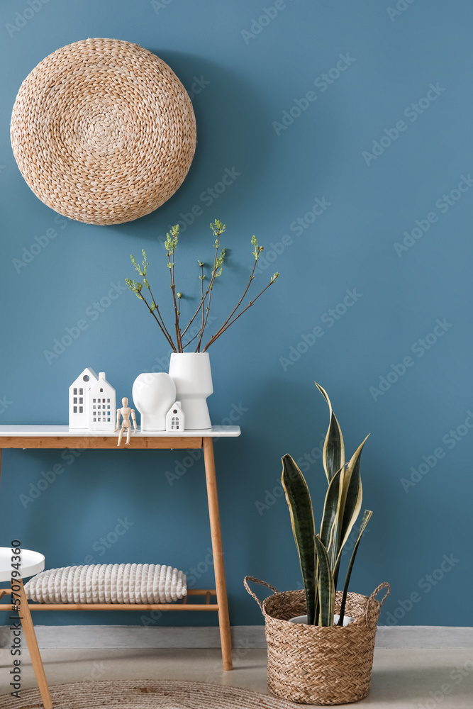 House candle holders, wooden mannequin and houseplant on table near blue wall