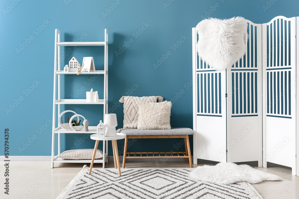 Interior of living room with house candle holders on end table, shelving unit and folding screen nea