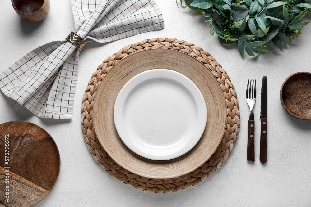 Beautiful table setting with mistletoe wreath on white background