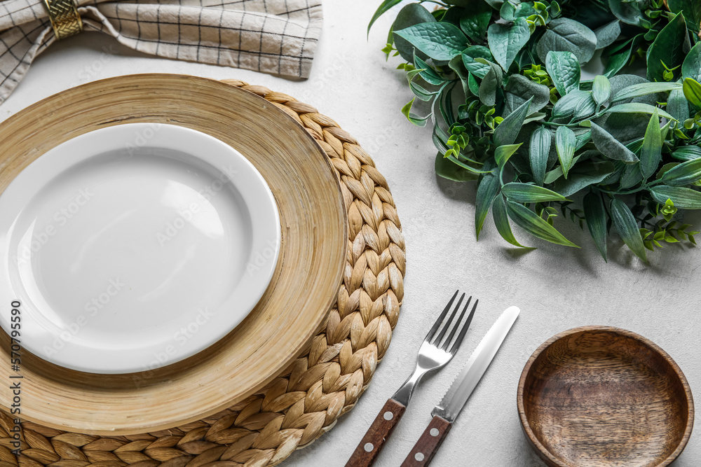 Beautiful table setting with mistletoe wreath on white background