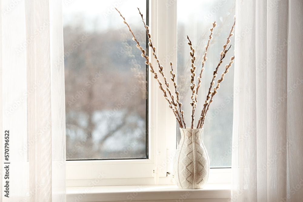 Vase with pussy willow branches on windowsill in room