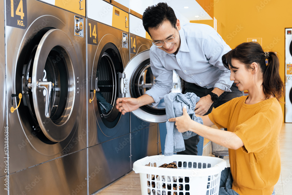 Asian people using qualified coin operated laundry machine in the public room to wash their cloths. 