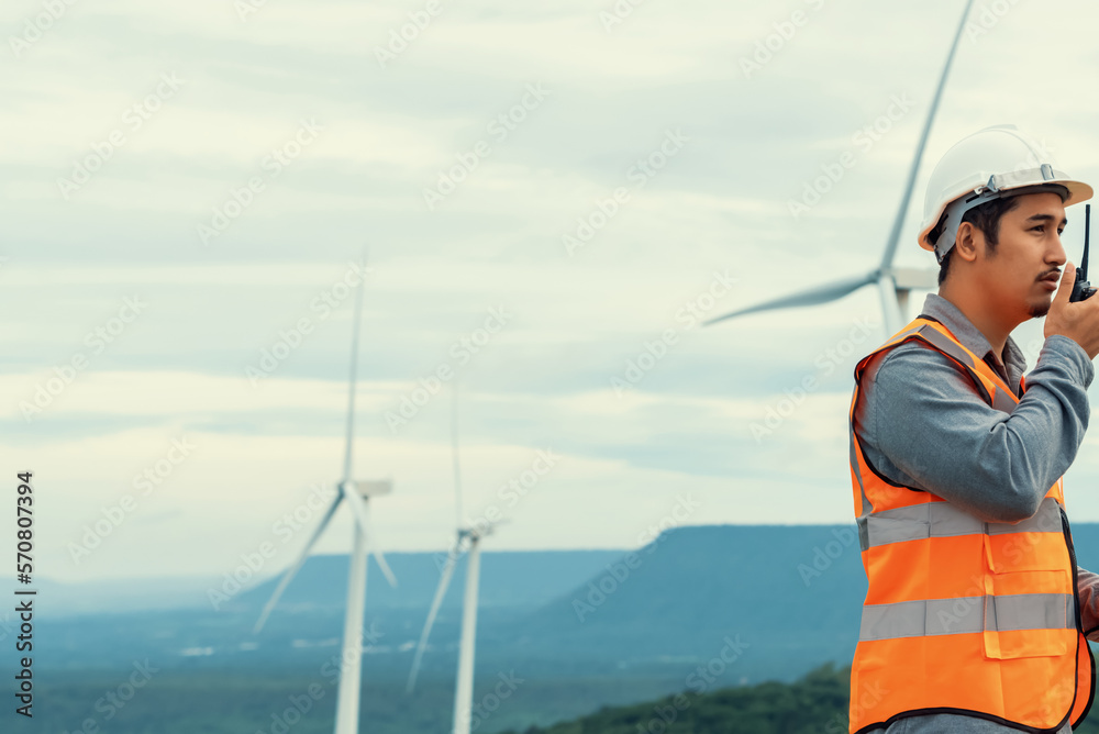 Engineer working on a wind farm atop a hill or mountain in the rural. Progressive ideal for the futu