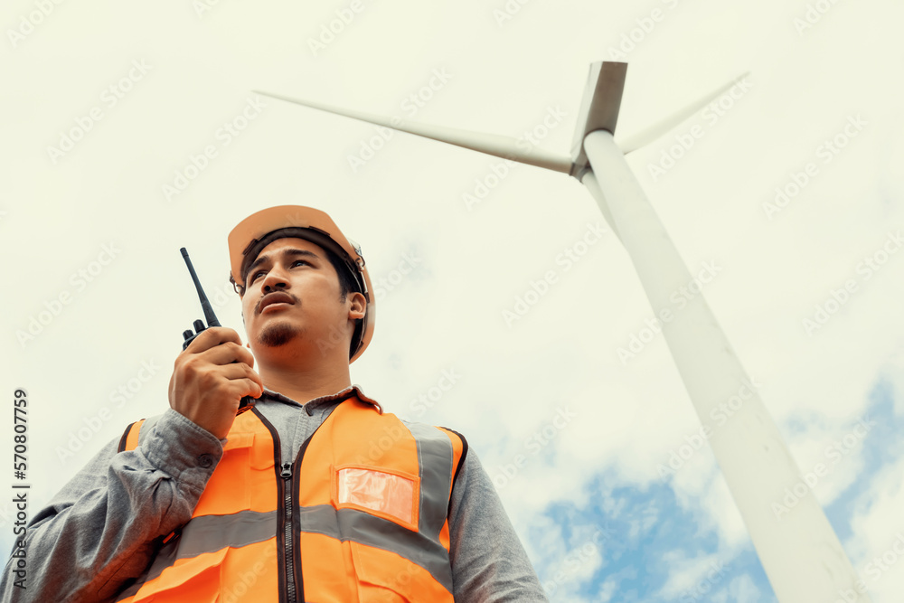 Engineer working on a wind farm atop a hill or mountain in the rural. Progressive ideal for the futu